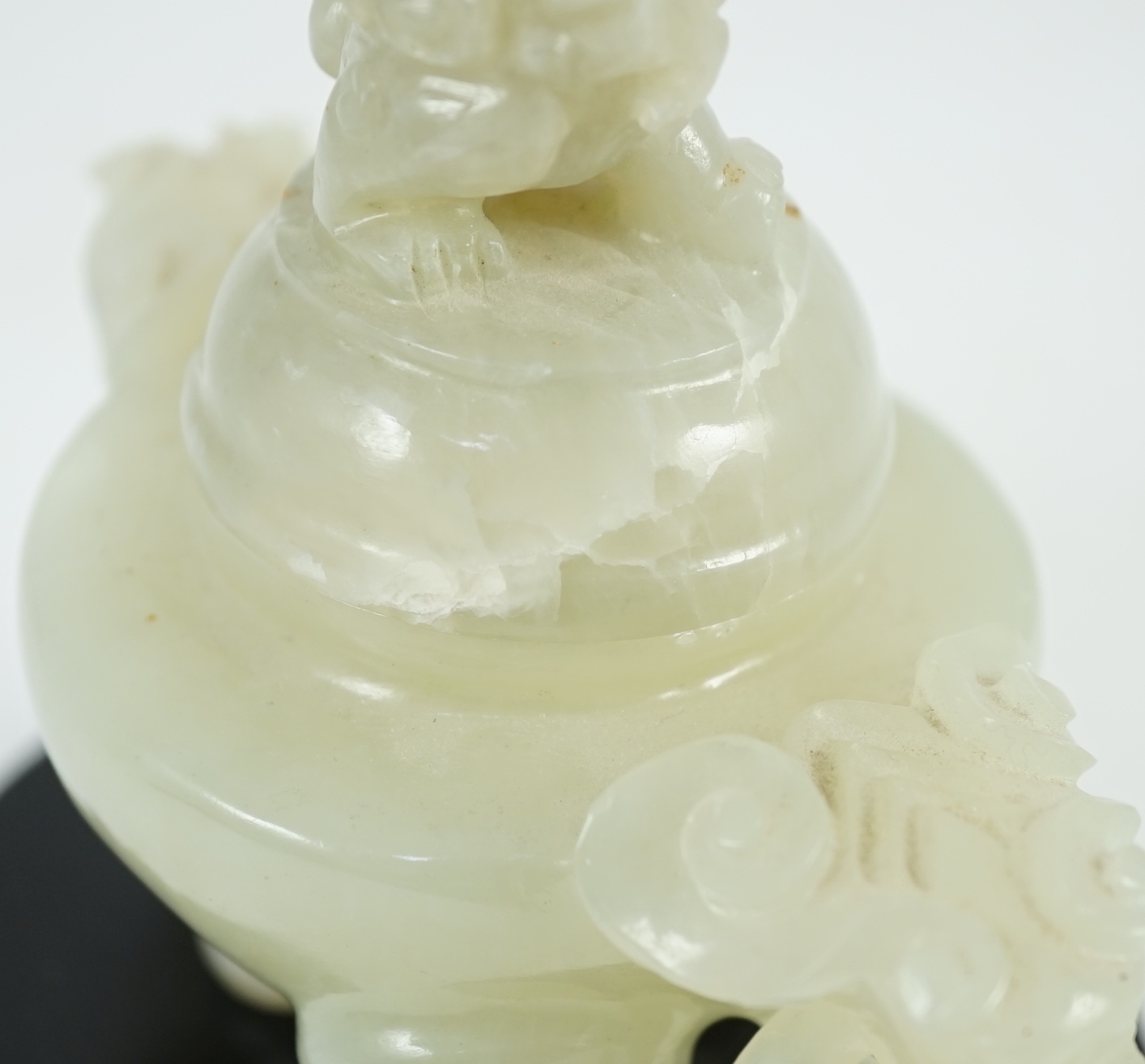 A Chinese pale celadon jade tripod censer cover, 20th century, 12cm wide, wood stand